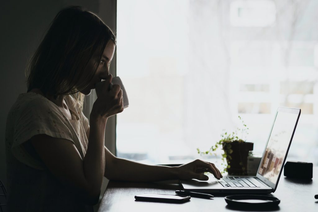 girl using laptop and drinking from the cup