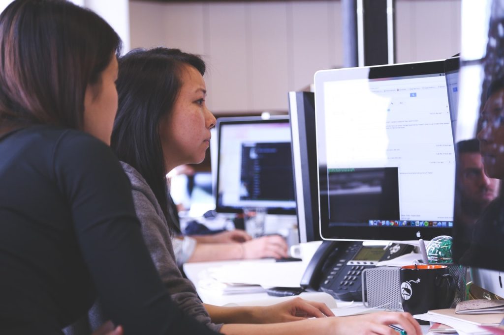 Two women sitting in front of PC