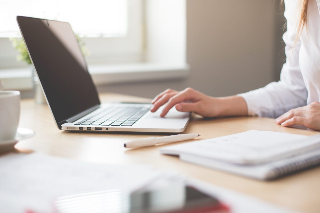 person using laptop on brown desk