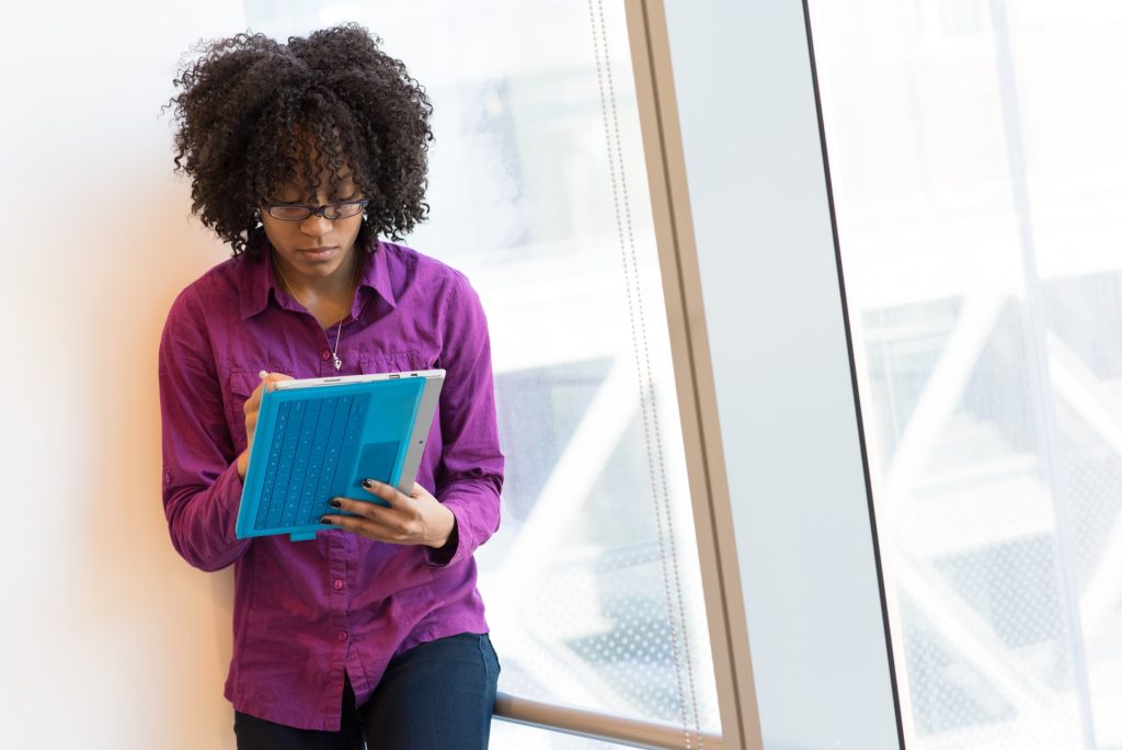 woman in purple shirt working on tablet