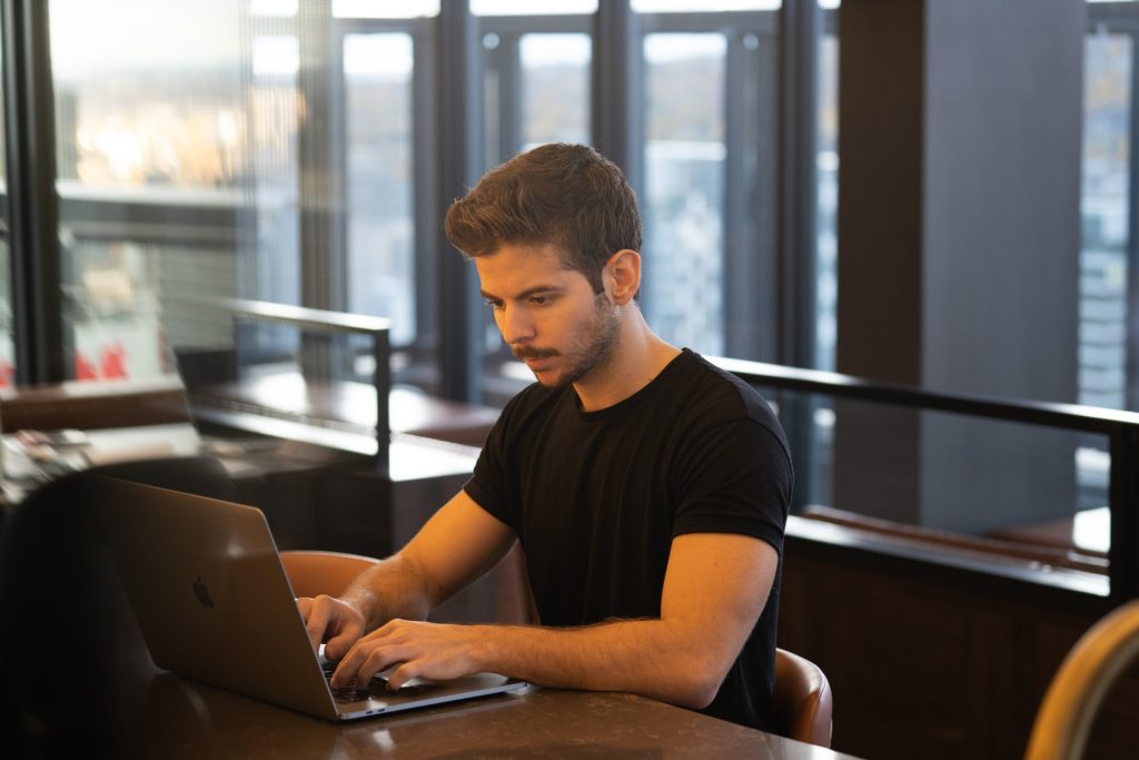 Man in black t-shirt using laptop in office