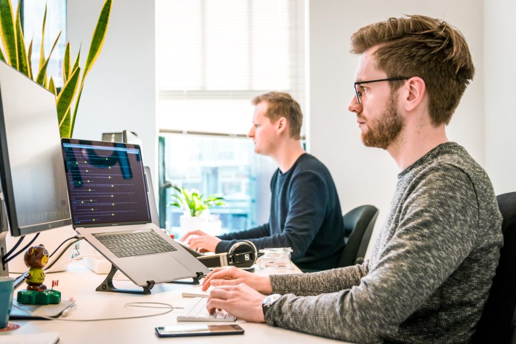 man in grey shirt looking at pc